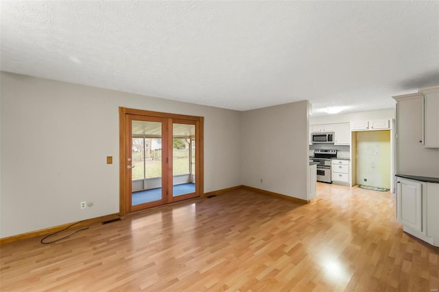 unfurnished living room featuring a textured ceiling and light wood-type flooring