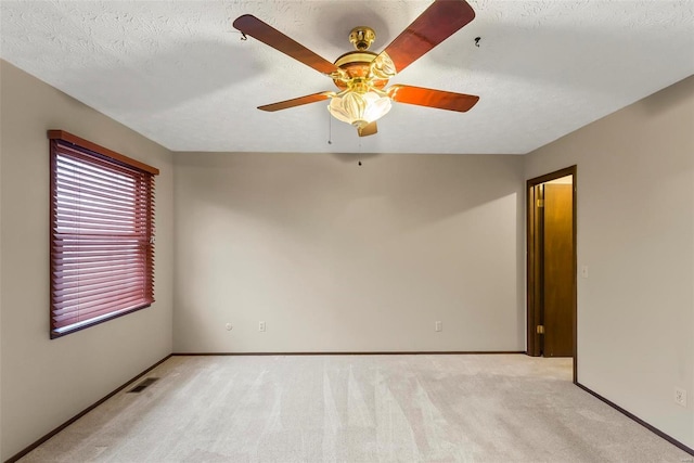 unfurnished room with ceiling fan, light colored carpet, and a textured ceiling