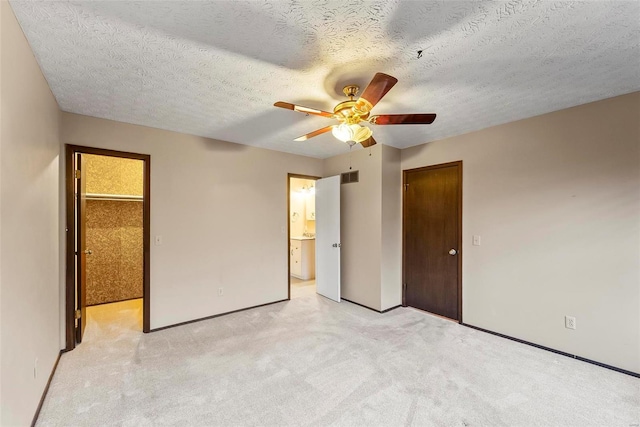 unfurnished bedroom featuring ceiling fan, ensuite bathroom, light colored carpet, and a textured ceiling