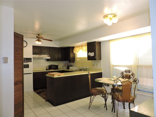 kitchen featuring black appliances, ceiling fan, tasteful backsplash, dark brown cabinets, and light tile patterned flooring