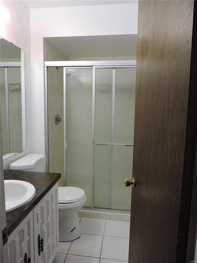 bathroom featuring tile patterned flooring, vanity, an enclosed shower, and toilet