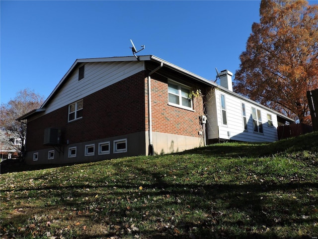 view of side of home with central AC unit and a lawn