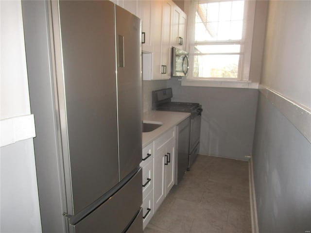 kitchen with black / electric stove, white cabinetry, sink, and fridge