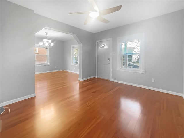 interior space featuring hardwood / wood-style floors, ceiling fan with notable chandelier, and a healthy amount of sunlight