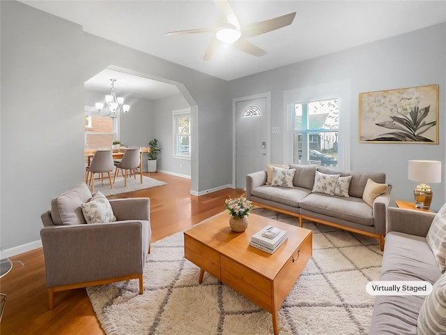 living room with ceiling fan with notable chandelier and wood-type flooring