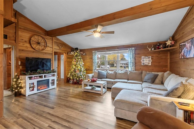 living room with hardwood / wood-style floors, vaulted ceiling with beams, ceiling fan, and wooden walls