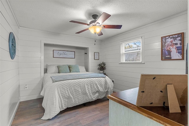 bedroom with a textured ceiling, dark hardwood / wood-style floors, and ceiling fan