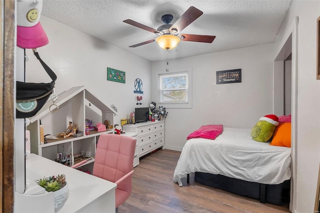 bedroom featuring ceiling fan, wood-type flooring, and a textured ceiling