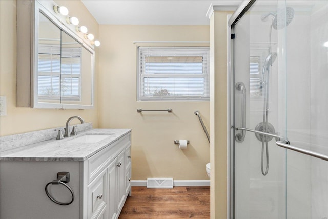 bathroom with walk in shower, a healthy amount of sunlight, wood-type flooring, and vanity