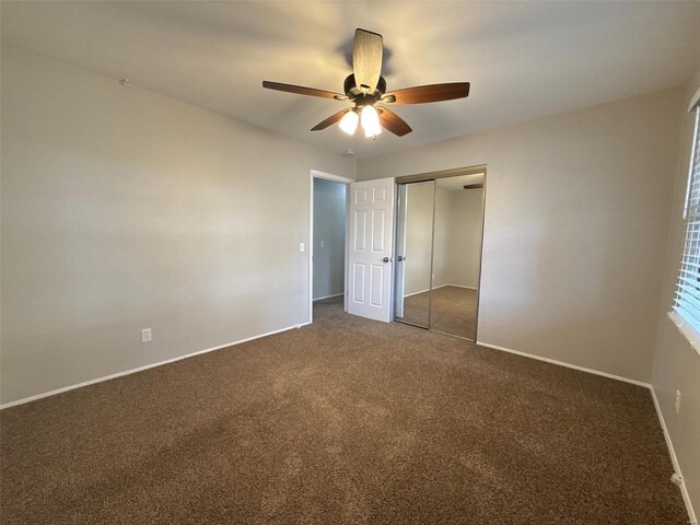 unfurnished bedroom featuring ceiling fan, a closet, and dark colored carpet