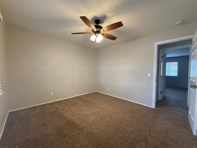 spare room with ceiling fan and dark colored carpet