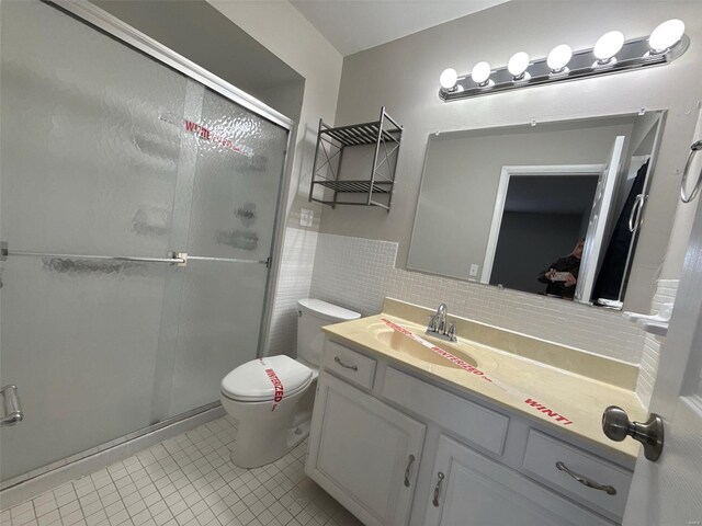 bathroom featuring tile patterned floors, vanity, a shower with door, and tile walls