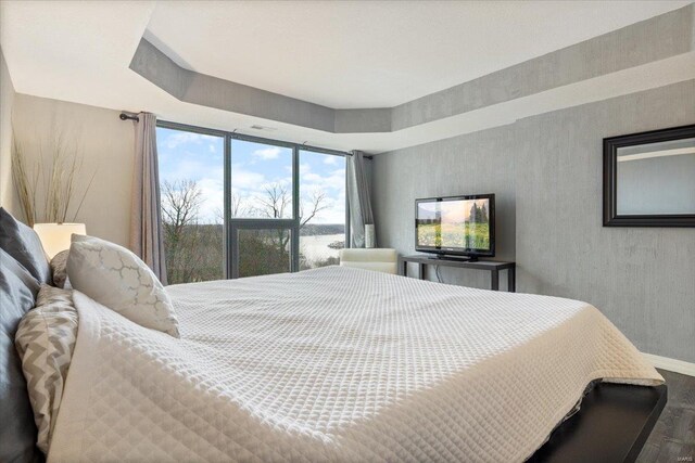 bedroom featuring hardwood / wood-style flooring and a tray ceiling