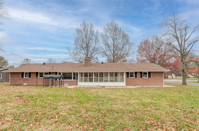 back of house featuring a sunroom and a lawn