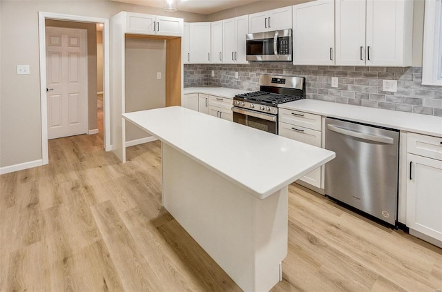 kitchen featuring tasteful backsplash, stainless steel appliances, light hardwood / wood-style flooring, white cabinets, and a center island