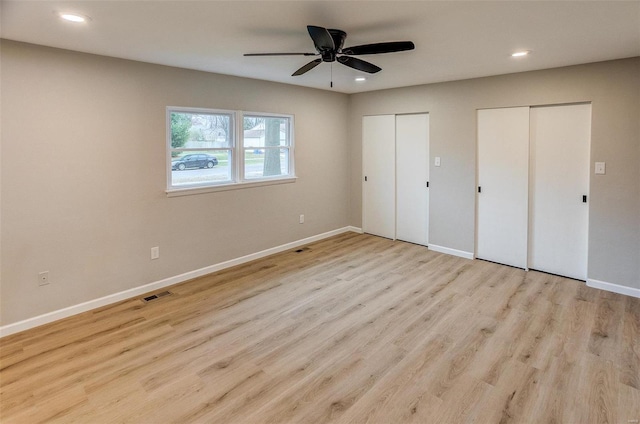 unfurnished bedroom featuring multiple closets, ceiling fan, and light hardwood / wood-style flooring