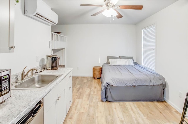 bedroom with a wall mounted AC, light wood-type flooring, ceiling fan, and sink