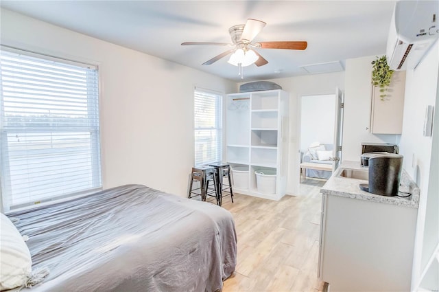 bedroom featuring ceiling fan, light hardwood / wood-style floors, a wall unit AC, and multiple windows