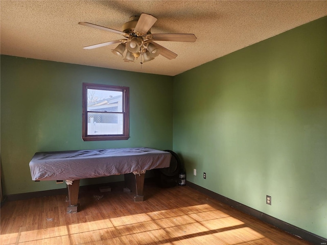 unfurnished bedroom featuring ceiling fan, light hardwood / wood-style floors, a textured ceiling, and pool table