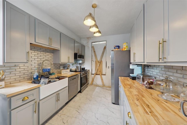 kitchen with decorative backsplash, hanging light fixtures, appliances with stainless steel finishes, and wooden counters