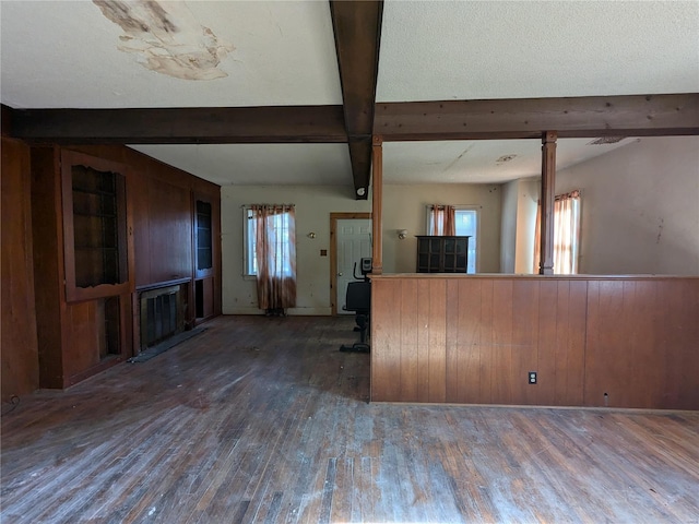 kitchen featuring wooden walls, dark hardwood / wood-style flooring, beamed ceiling, and a healthy amount of sunlight