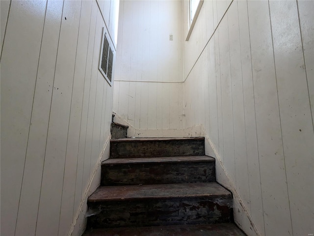 staircase featuring wooden walls