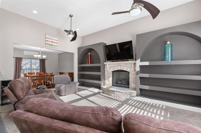 living room with a fireplace, carpet floors, built in features, and ceiling fan with notable chandelier