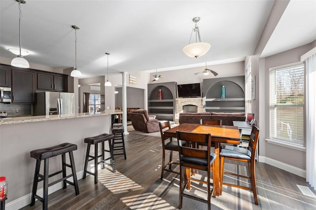 dining space with built in shelves, a fireplace, and dark wood-type flooring