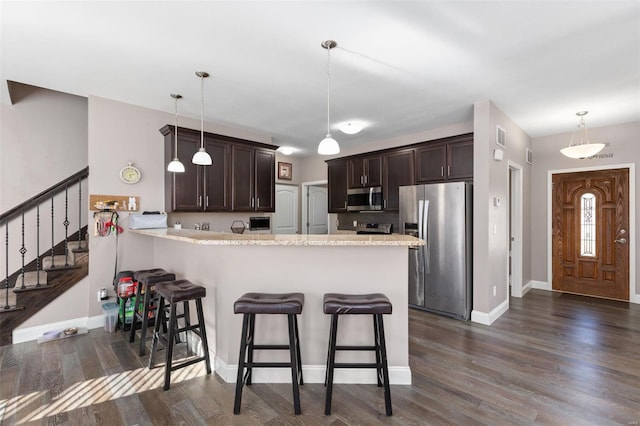 kitchen with kitchen peninsula, a breakfast bar, stainless steel appliances, and hanging light fixtures