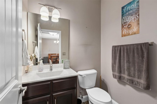 bathroom with toilet, vanity, and an inviting chandelier