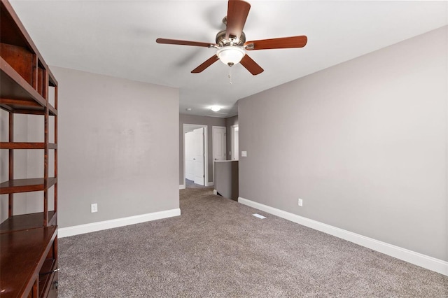 spare room featuring dark colored carpet and ceiling fan