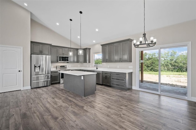 kitchen featuring stainless steel appliances, sink, decorative light fixtures, high vaulted ceiling, and a center island