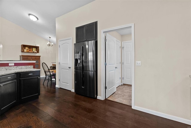 kitchen featuring an inviting chandelier, dark hardwood / wood-style floors, black fridge with ice dispenser, lofted ceiling, and light stone countertops