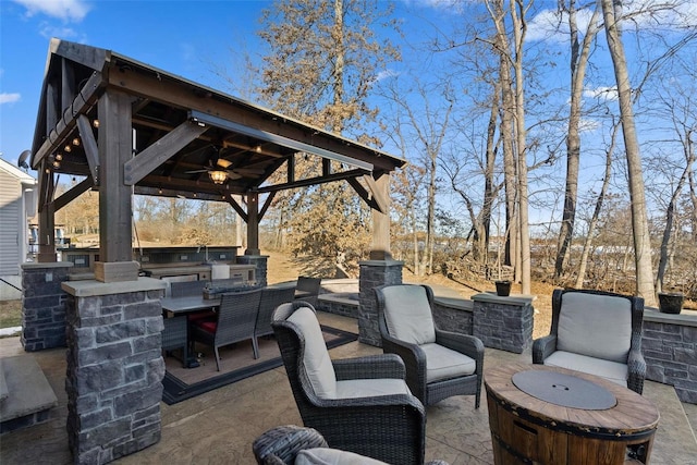 view of patio with ceiling fan, an outdoor bar, a gazebo, and an outdoor kitchen