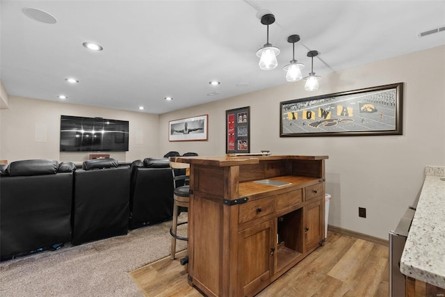 kitchen with decorative light fixtures, a kitchen bar, and light hardwood / wood-style floors