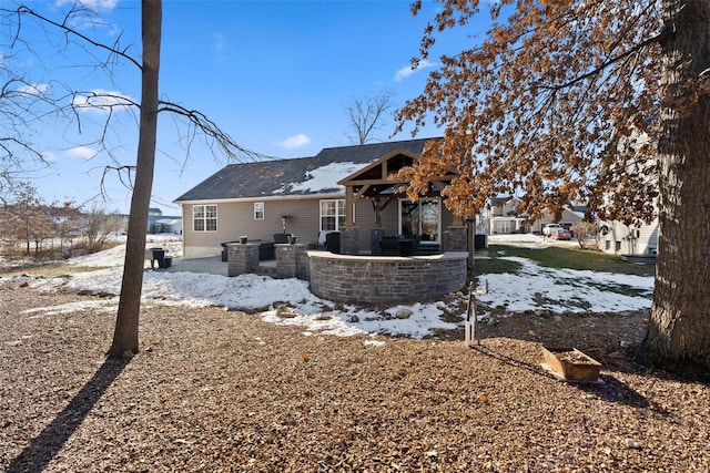 snow covered rear of property featuring a patio