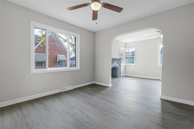 unfurnished living room with plenty of natural light, ceiling fan, and dark wood-type flooring