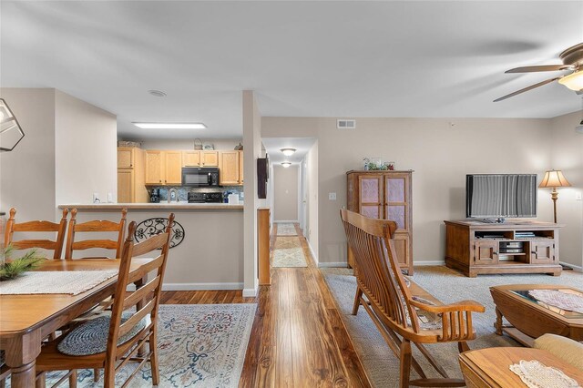 dining area with ceiling fan, light hardwood / wood-style floors, and sink