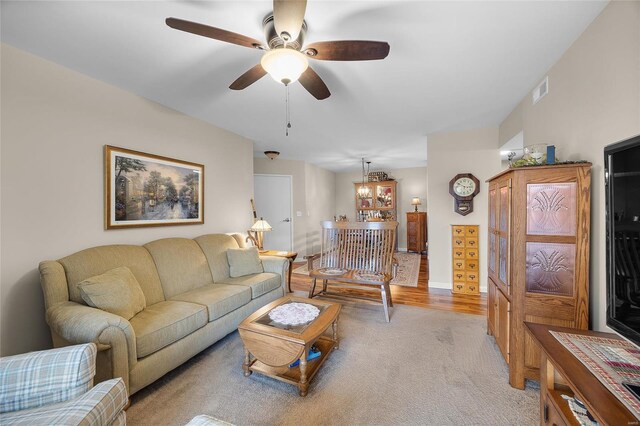 living room with ceiling fan with notable chandelier and light wood-type flooring