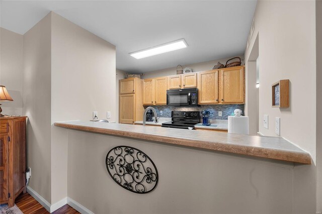 kitchen with sink, light brown cabinets, decorative backsplash, black appliances, and hardwood / wood-style flooring