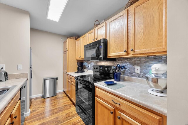 kitchen featuring light brown cabinetry, backsplash, light hardwood / wood-style flooring, and black appliances