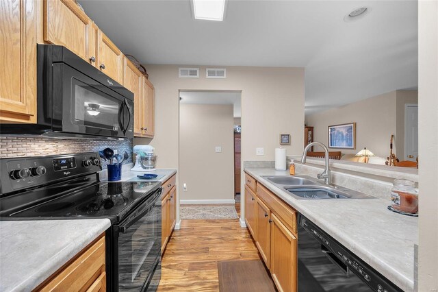 kitchen featuring light brown cabinets, backsplash, black appliances, sink, and light hardwood / wood-style flooring