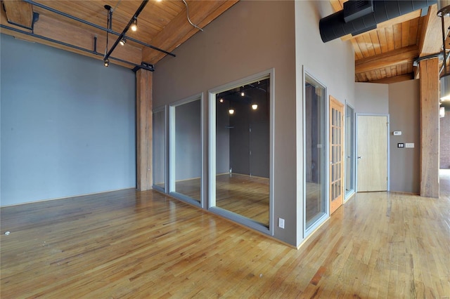 spare room featuring wood ceiling, a high ceiling, and light hardwood / wood-style floors