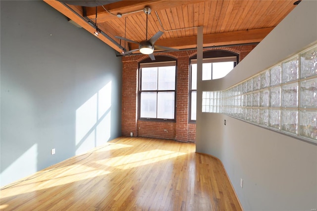 spare room featuring beam ceiling, light wood-type flooring, ceiling fan, and wood ceiling