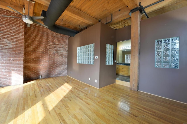 unfurnished living room featuring beam ceiling, hardwood / wood-style floors, and a towering ceiling