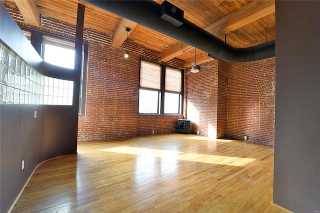 unfurnished room with beam ceiling, a towering ceiling, wooden ceiling, and wood-type flooring