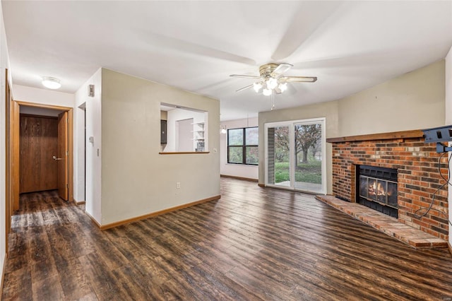 unfurnished living room with ceiling fan, dark wood-type flooring, and a brick fireplace