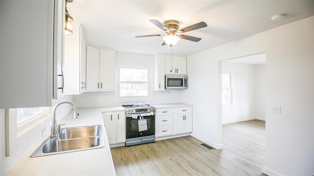 kitchen featuring sink, light hardwood / wood-style flooring, ceiling fan, white cabinetry, and stainless steel appliances