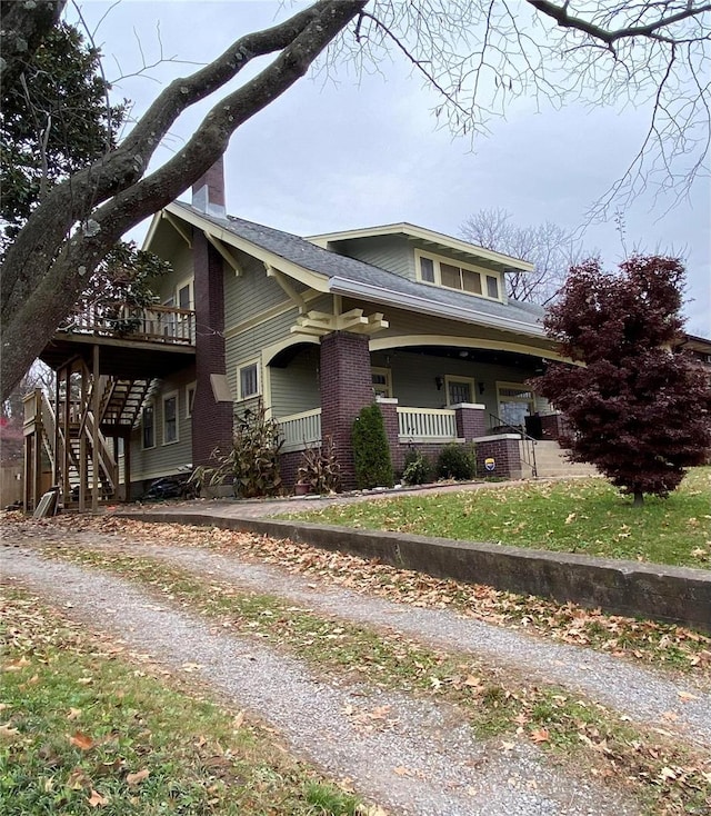 view of front of home featuring brick siding, covered porch, and stairs