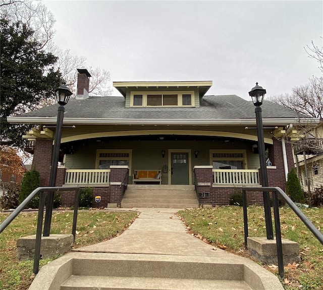 view of front facade with brick siding and covered porch